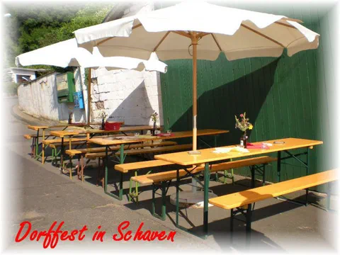 Biertische unter Sonnenschirmen vor der Festscheune